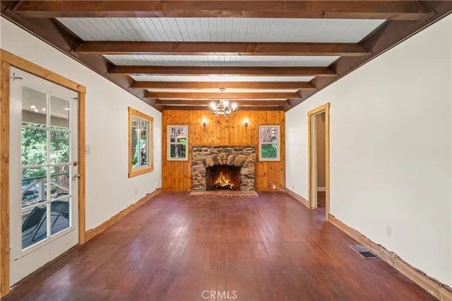 a view of an empty room with wooden floor fireplace and a window