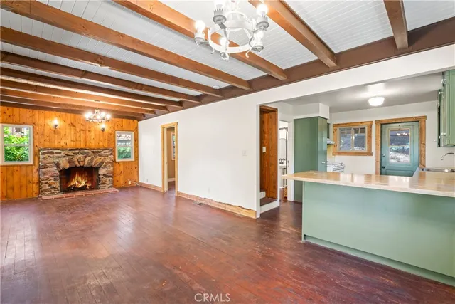 a view of an empty room with wooden floor fireplace and a window