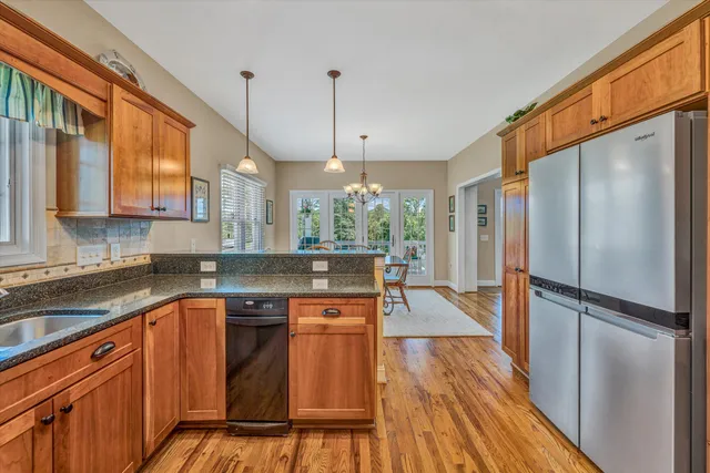 a kitchen with stainless steel appliances granite countertop a refrigerator a sink dishwasher a stove and white countertops with wooden floor