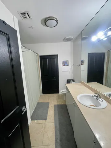 a bathroom with a granite countertop sink a mirror and shower