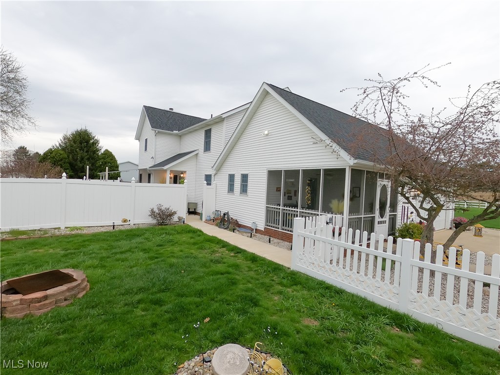 2421 McCoy Road Wooster, OH 44691 - Photo 38 of 39 Back of house with a fenced backyard, a sunroom, and a lawn