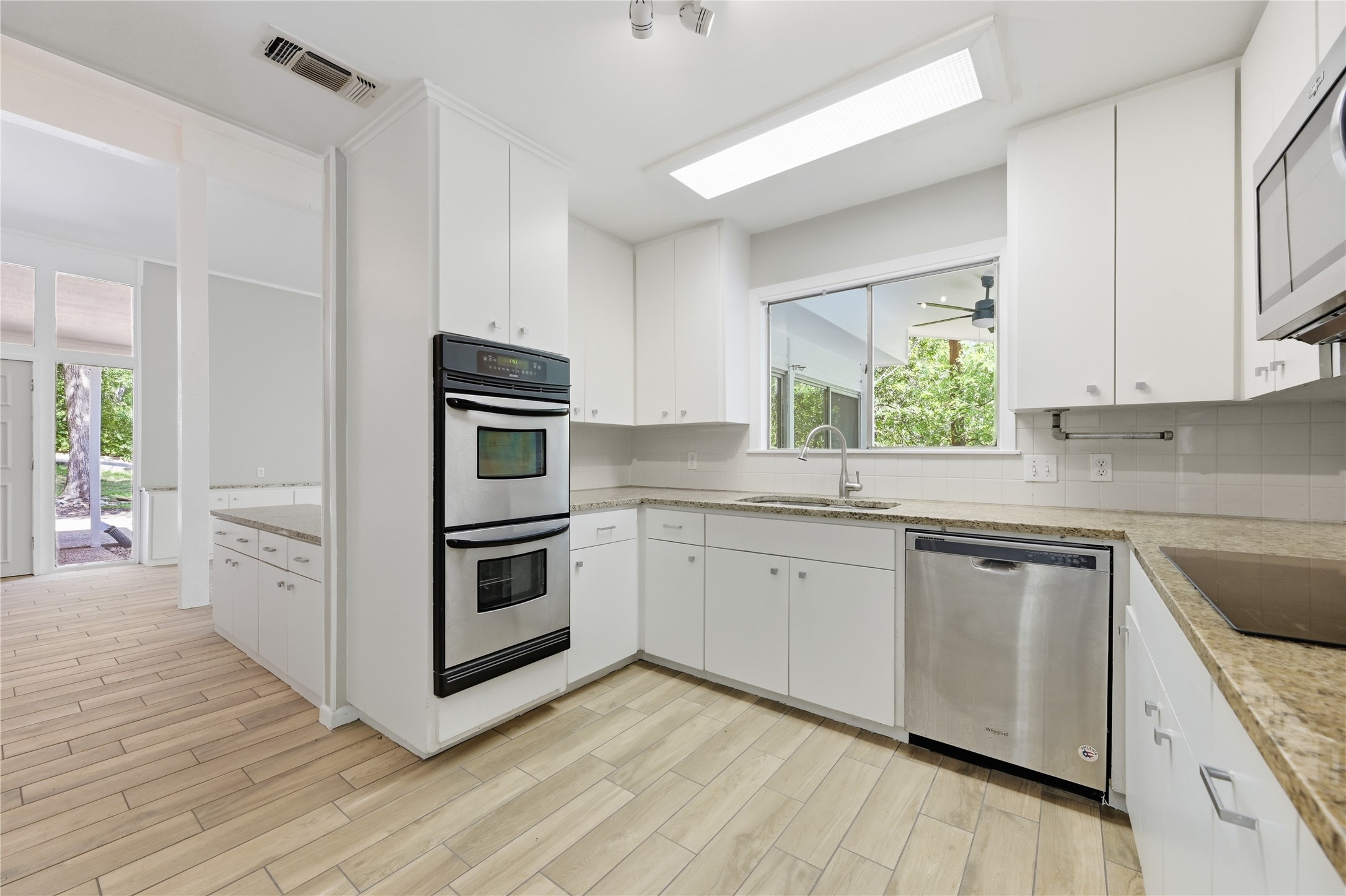 7 Hull Circle Austin, TX 78746 - Photo 11 of 14 Kitchen featuring white cabinets, wood tiled floors, stainless steel appliances, and decorative backsplash