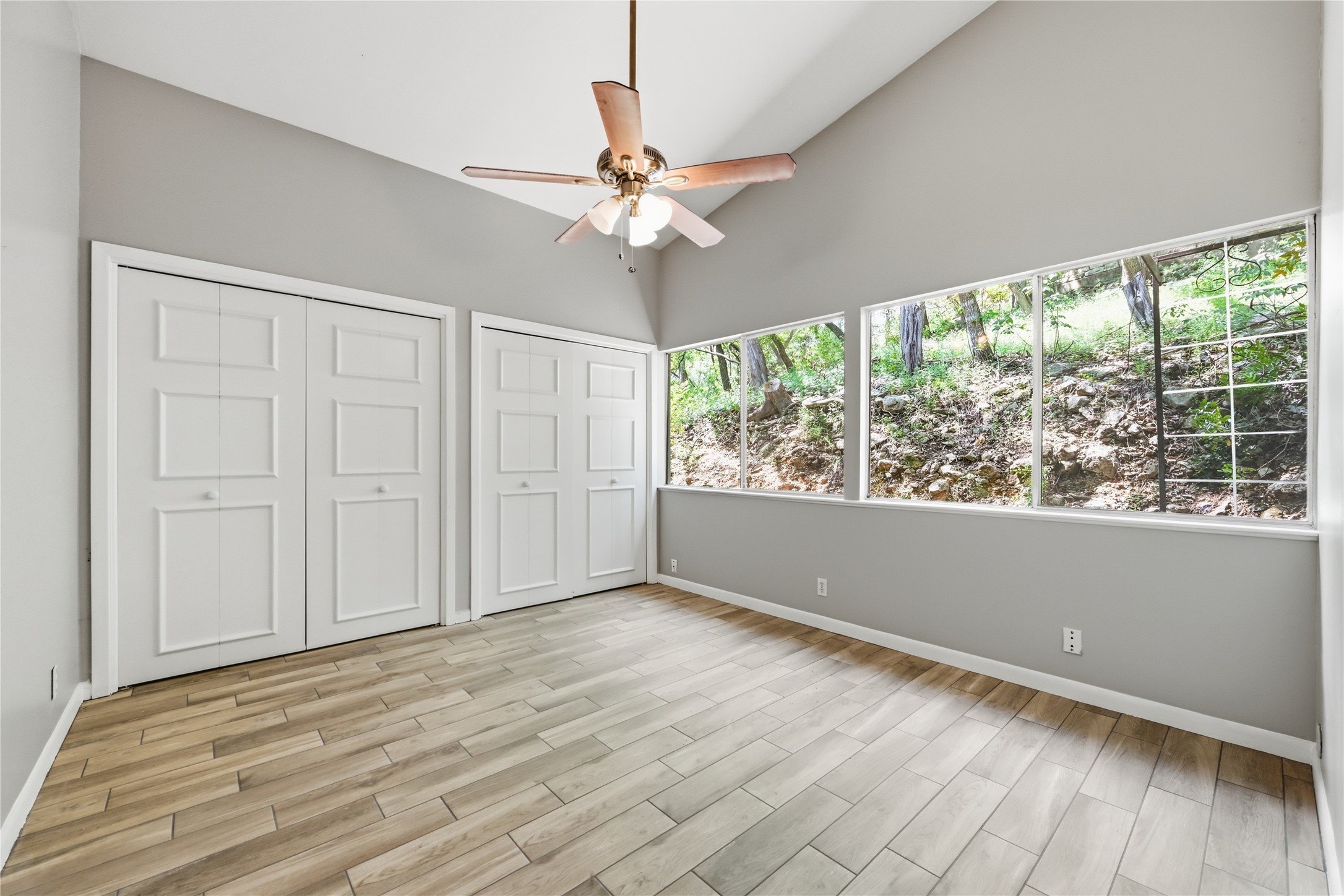 7 Hull Circle Austin, TX 78746 - Photo 6 of 14 Unfurnished bedroom featuring two closets, wood finish floors, vaulted ceiling, and a ceiling fan