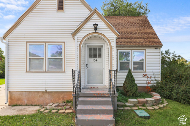 154 South State Street Morgan, UT 84050 - Photo 19 of 25 White siding exterior with a shingled roof, arched entry frame, and black wrought iron handrails