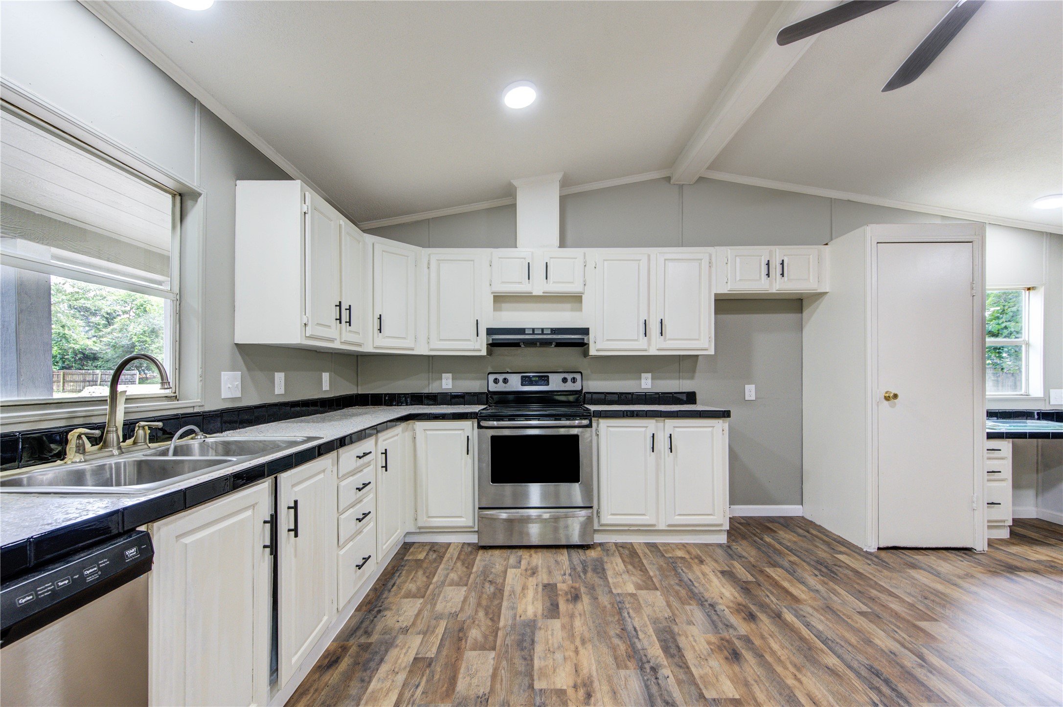 30226 Davis Street Magnolia, TX 77355 - Photo 20 of 50 This kitchen features modern stainless steel appliances, ample white cabinetry, and sleek countertops. It offers a spacious layout with a double sink, stylish wood flooring, and plenty of natural light, making it perfect for cooking and entertaining.