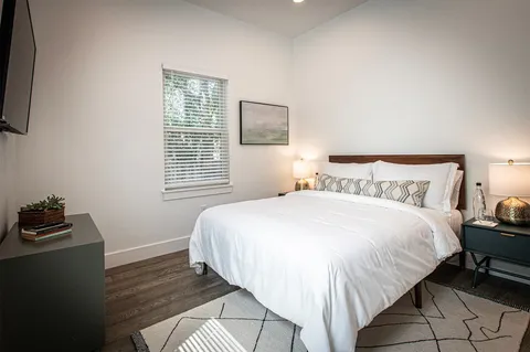 a bedroom with a bed wooden floor and window