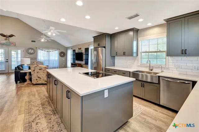a kitchen with stainless steel appliances kitchen island granite countertop a sink and a refrigerator