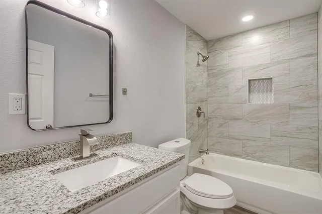 a bathroom with a granite countertop sink toilet and shower
