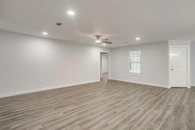 a view of an empty room with wooden floor and a window
