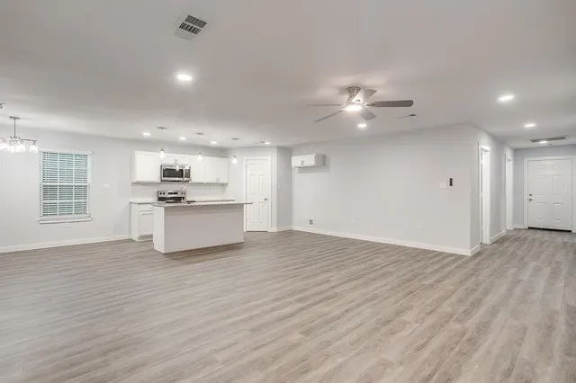 a view of kitchen with stove and white cabinets with wooden floor