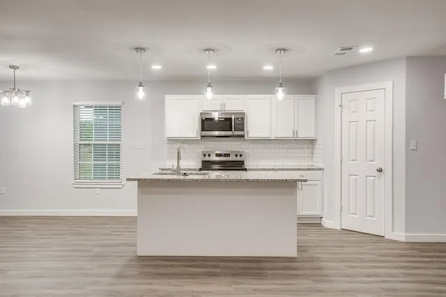a kitchen with stainless steel appliances granite countertop a stove a sink and a microwave
