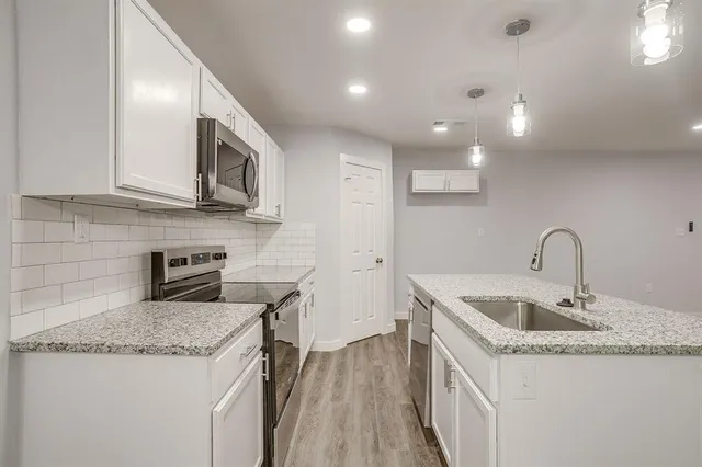 a kitchen with granite countertop a sink and a stove top oven
