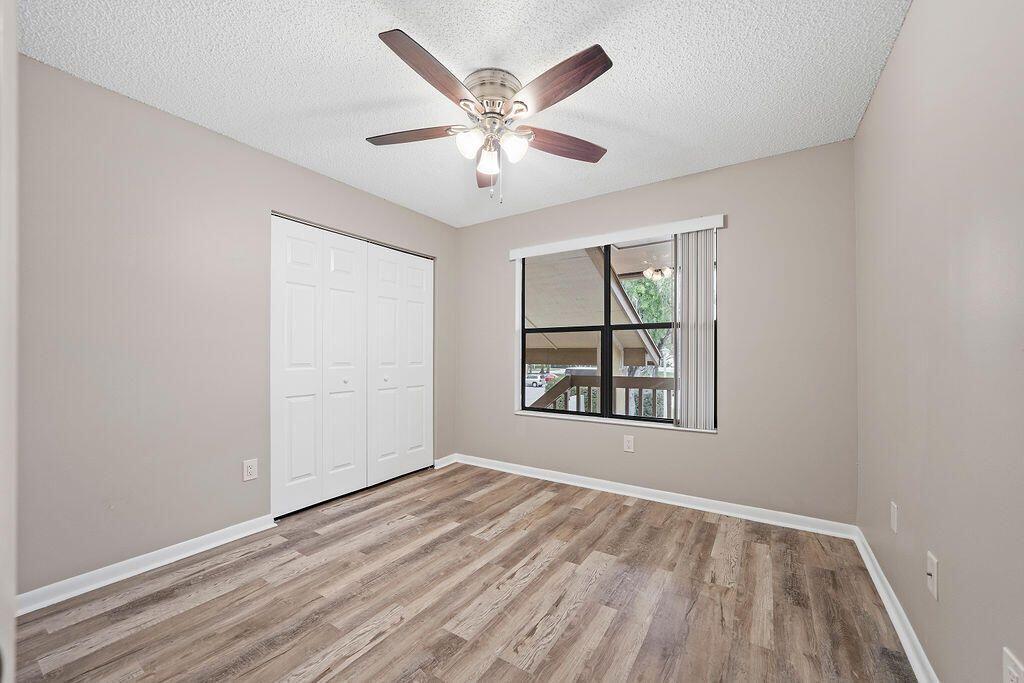 12969 Pennypacker Trail, Unit 15 Wellington, FL 33414 - Photo 19 of 24 an empty room with wooden floor chandelier fan and windows