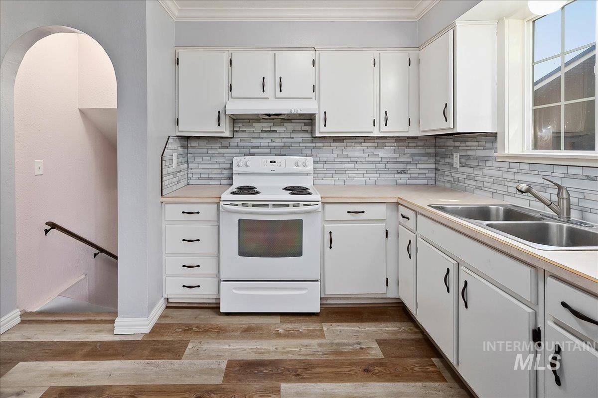 1940 Q Street Heyburn, ID 83336 - Photo 13 of 30 Kitchen featuring white cabinetry, light countertops, a mosaic tile backsplash, and a double basin stainless steel sink with a gooseneck faucet