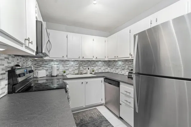 a kitchen with stainless steel appliances granite countertop a refrigerator a stove and a sink
