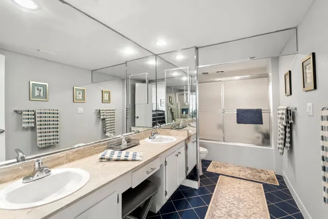 a bathroom with a sink double vanity granite tub shower and a mirror