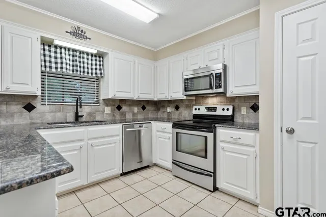 a kitchen with stainless steel appliances granite countertop white cabinets sink and a microwave