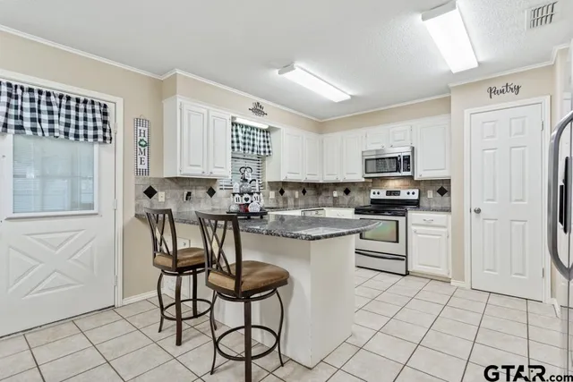 a kitchen with white cabinets and appliances