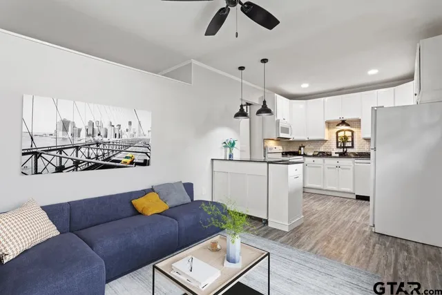 a kitchen with stainless steel appliances kitchen island granite countertop a refrigerator a stove and white cabinets with wooden floor