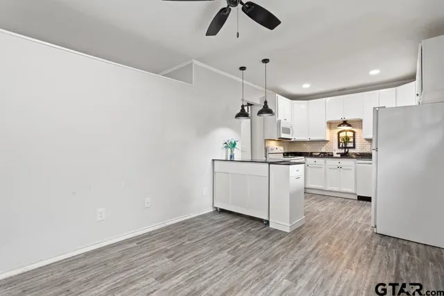 a kitchen with kitchen island white cabinets and wooden floor