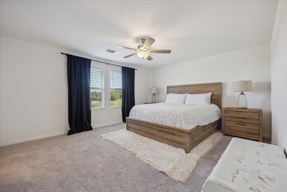 208 Night Riders Way Jarrell, TX 76537 - Photo 14 of 31 a bedroom with a large bed and a chandelier