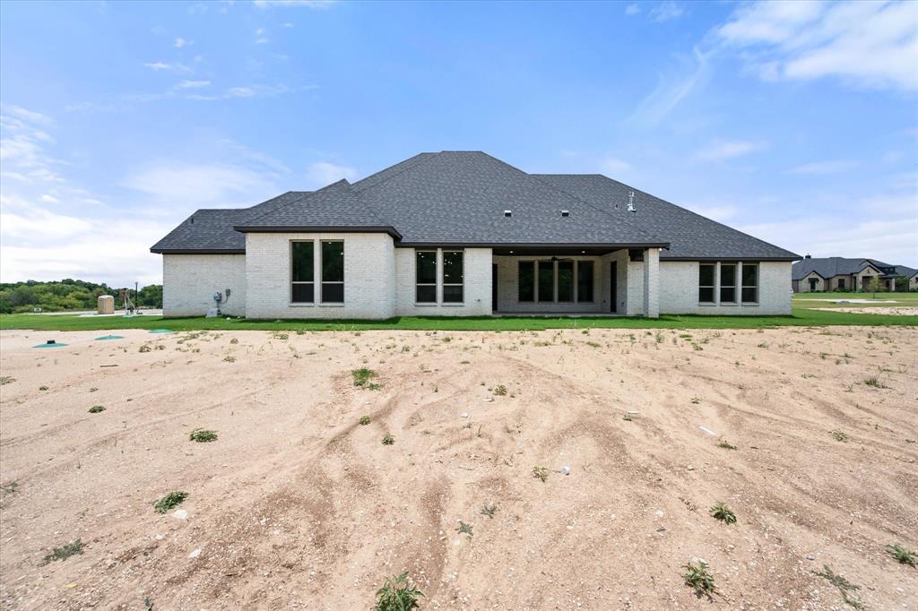 6610 Waggoner Way Midlothian, TX 76065 - Photo 39 of 40 Rear exterior showcasing a white brick facade and a dark shingle roof