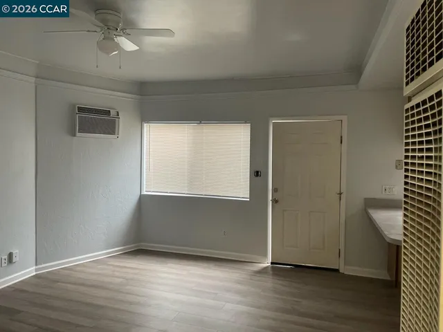 an empty room with wooden floor cabinet and windows