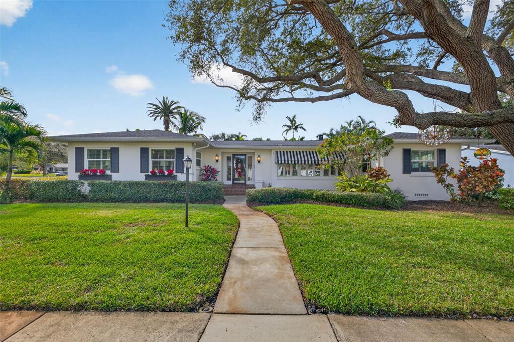 a view of a white house with a yard and potted plants
