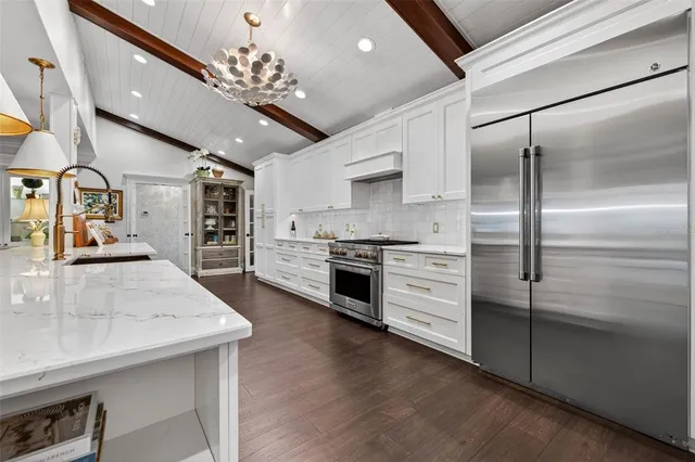 a kitchen with stainless steel appliances kitchen island granite countertop a refrigerator a sink dishwasher a stove and a dining table with wooden floor