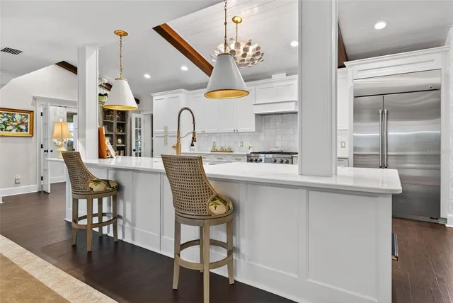 a kitchen with stainless steel appliances granite countertop a sink a stove and chairs
