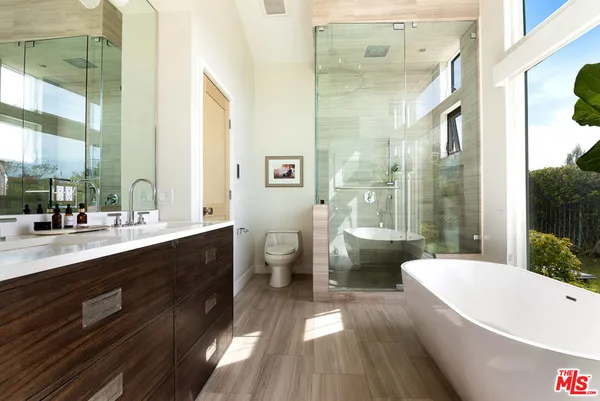 a bathroom with a double vanity sink a toilet a mirror and bathtub