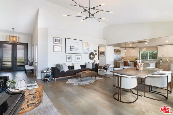a living room with furniture a chandelier fan and a window