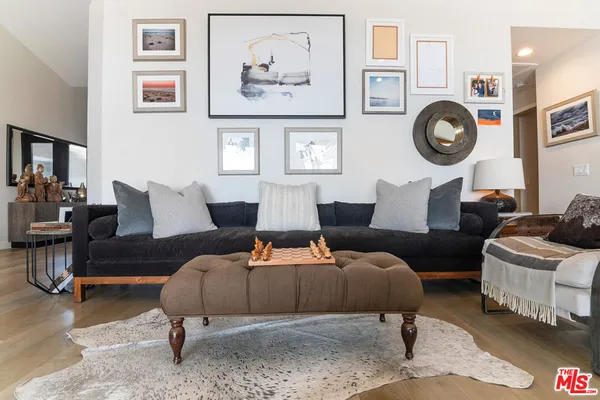 a living room with furniture a rug and wall paintings