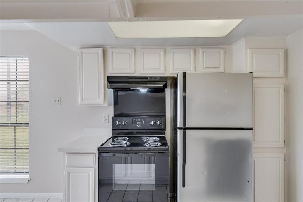 4544 Chaha Road, Unit 106 Garland, TX 75043 - Photo 11 of 17 Kitchen featuring white cabinets, black range with electric cooktop, stainless steel fridge, and plenty of natural light