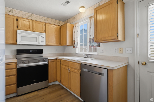794 East 950 S Street Provo, UT 84606 - Photo 9 of 28 Kitchen featuring light wood cabinetry, a stainless steel range, a built-in microwave, a white double-basin sink with a chrome faucet, and wood-finish flooring