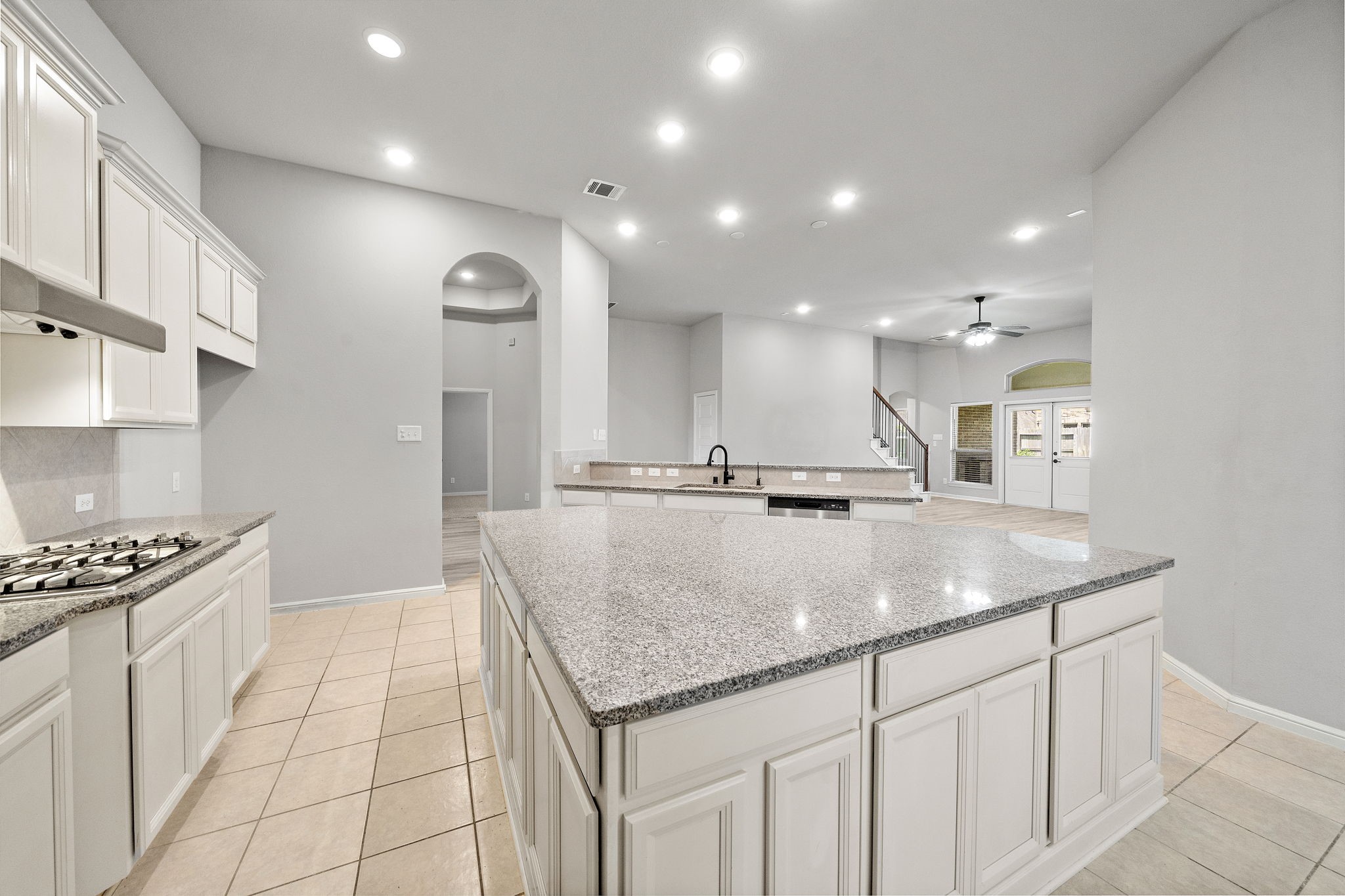 27924 Seger Bnd Trail Spring, TX 77386 - Photo 13 of 21 A spacious, open-concept kitchen with modern lighting, a large island with granite countertops, and ample cabinet space. The kitchen seamlessly connects to a bright living area with high ceilings and a ceiling fan, offering a perfect layout for entertaining.