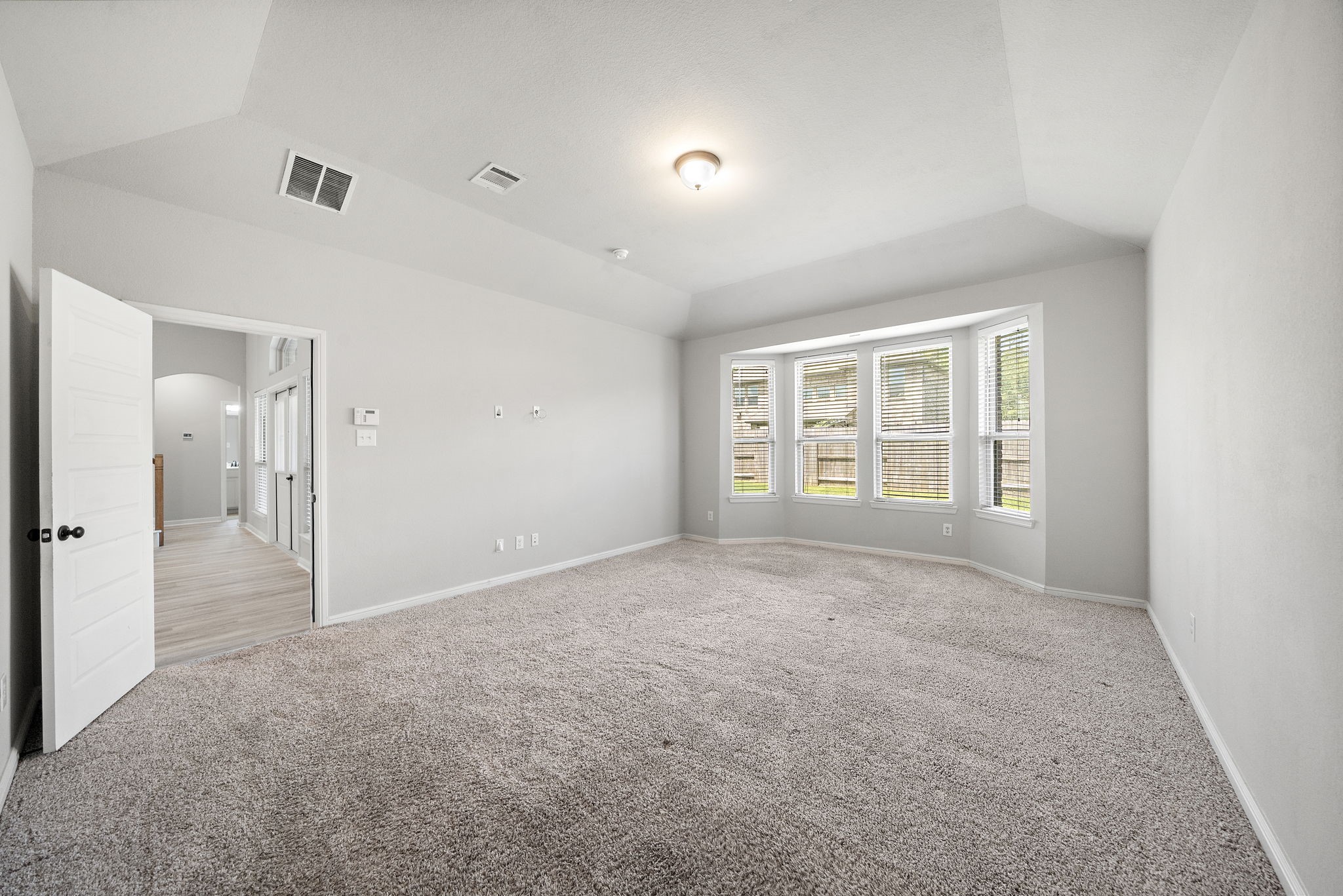 27924 Seger Bnd Trail Spring, TX 77386 - Photo 17 of 21 The master is a carpeted room with neutral walls and a vaulted ceiling features a large bay window allowing plenty of natural light. An open doorway leads to a hallway with hardwood flooring.