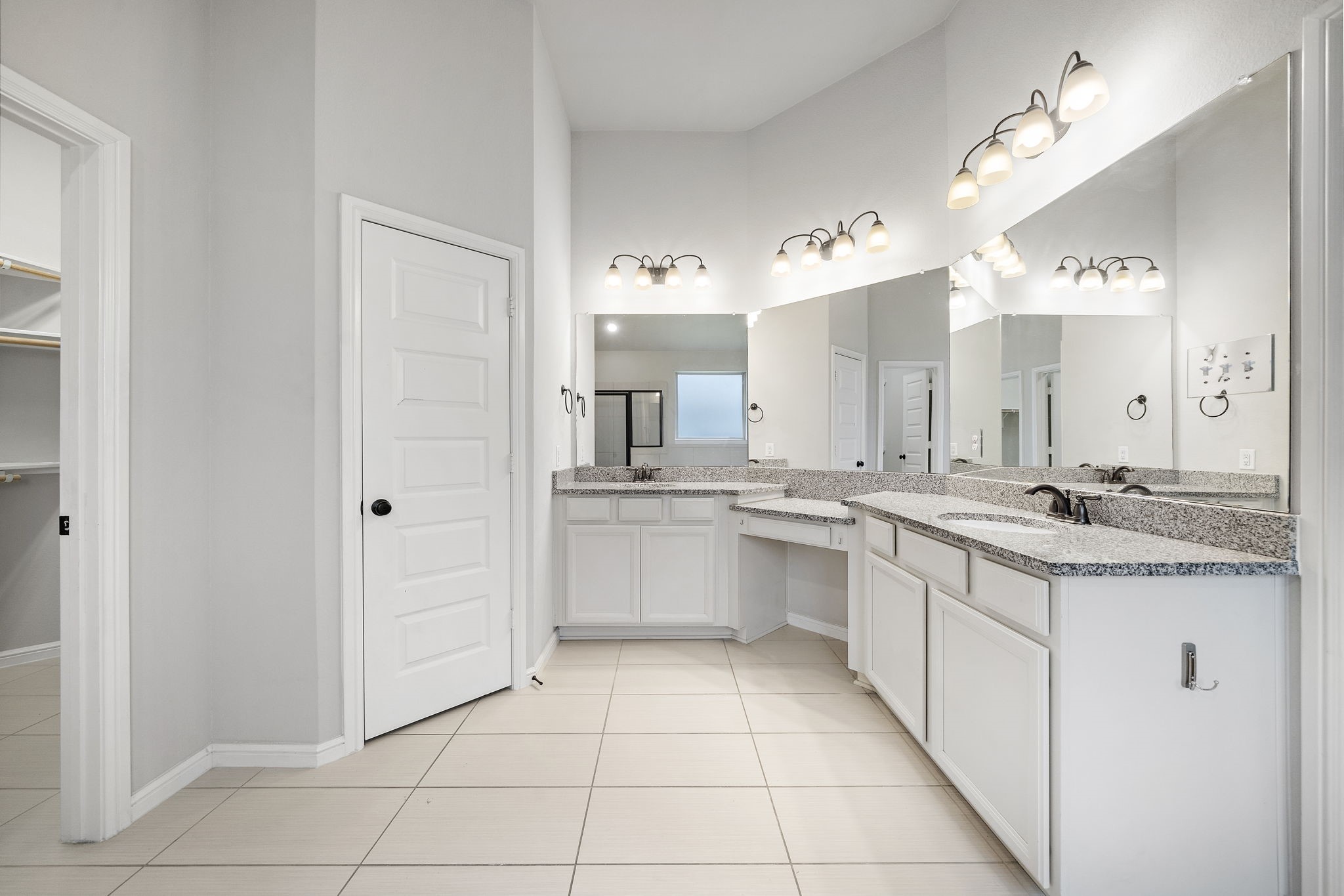 27924 Seger Bnd Trail Spring, TX 77386 - Photo 19 of 21 The primary bathroom features dual sinks with granite countertops, large mirrors, modern lighting, and neutral tile floors. It offers ample storage with white cabinetry and has a walk-in closet for convenience.