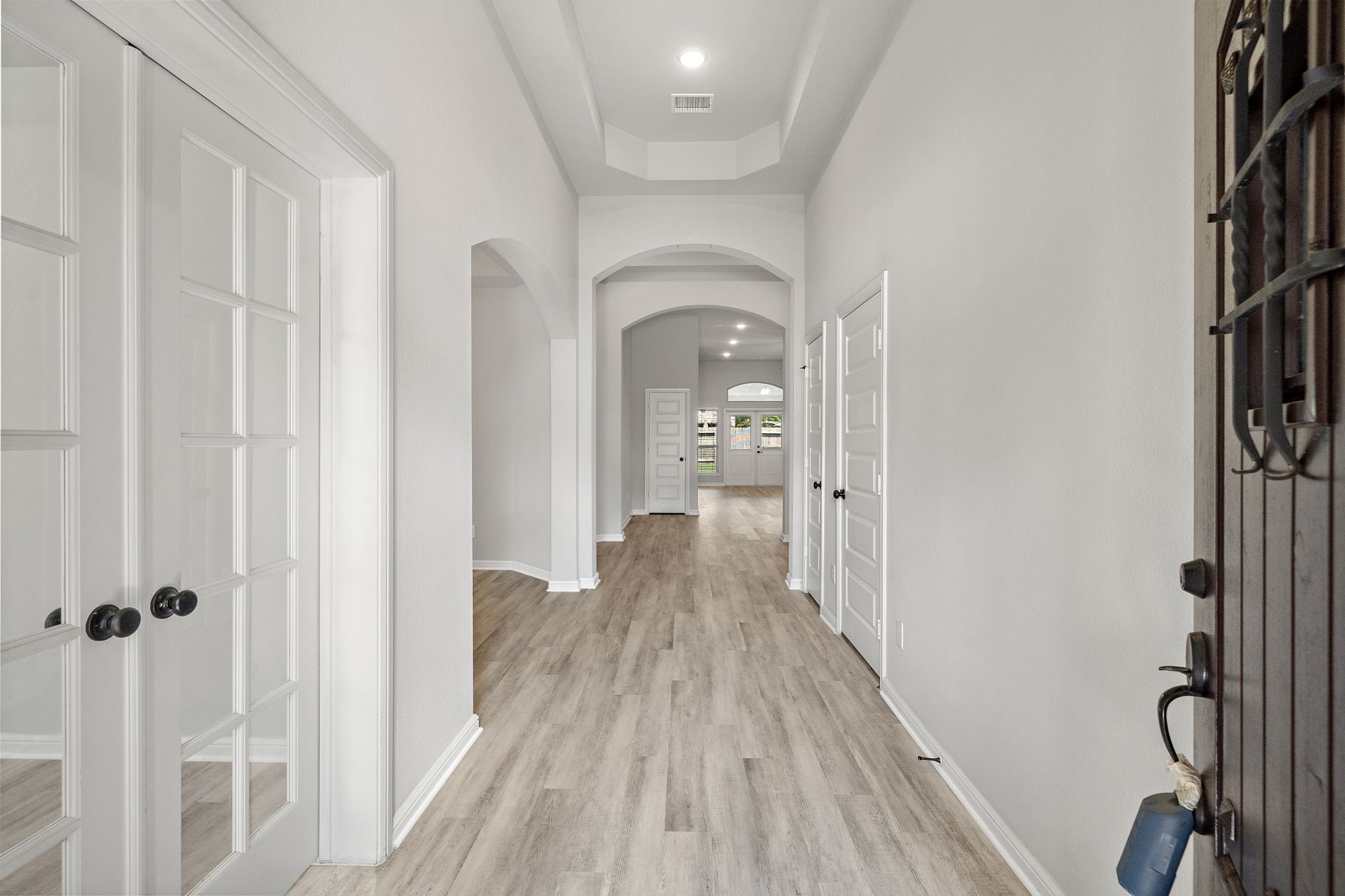 27924 Seger Bnd Trail Spring, TX 77386 - Photo 3 of 21 This home showcases a modern, spacious hallway with light wood flooring and elegant French doors. The high ceiling and neutral walls create a bright and inviting atmosphere, leading to a well-lit living space.