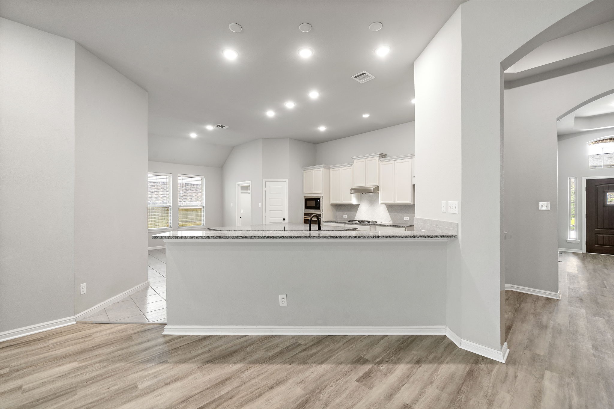 27924 Seger Bnd Trail Spring, TX 77386 - Photo 10 of 21 An open-concept kitchen with light cabinetry, granite countertops, and recessed lighting. The space features a breakfast bar, wood flooring, and ample natural light from large windows, creating an inviting and functional area.