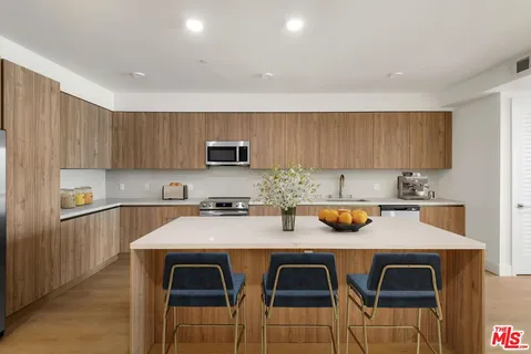 a kitchen with stainless steel appliances a stove a sink a microwave a refrigerator and cabinets