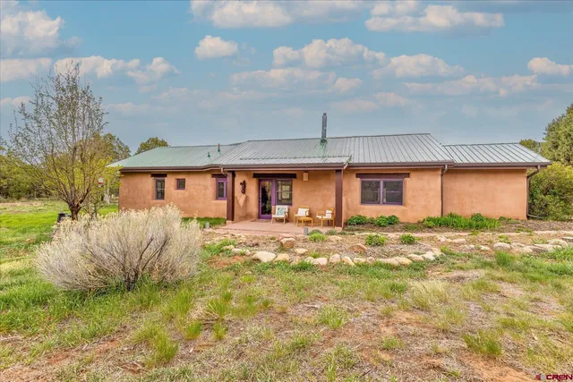 a front view of house with yard and trees in the background