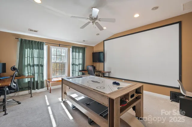 a room with a table chairs and projector with kitchen area