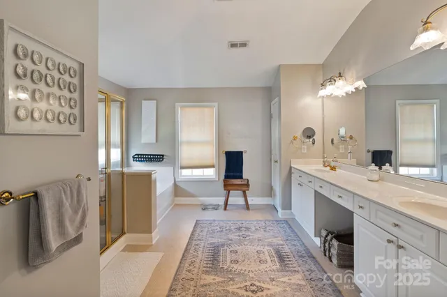 a spacious bathroom with a double vanity sink a mirror a bathtub and a shower