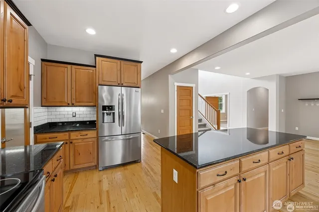 a kitchen with stainless steel appliances granite countertop a refrigerator a sink and a stove