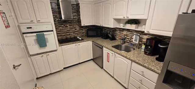 a kitchen with granite countertop white cabinets and white appliances