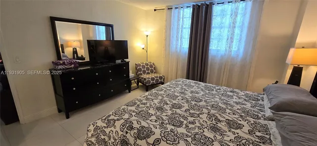 a bedroom with a bed and a flat tv screen on dresser