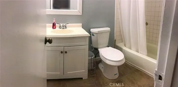 a white toilet sitting next to a white sink and vanity