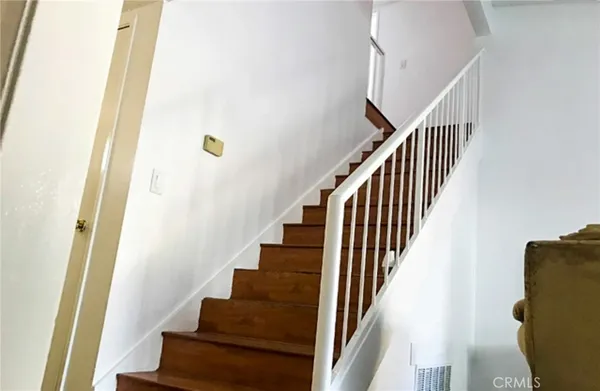 a view of staircase with wooden floor and white walls