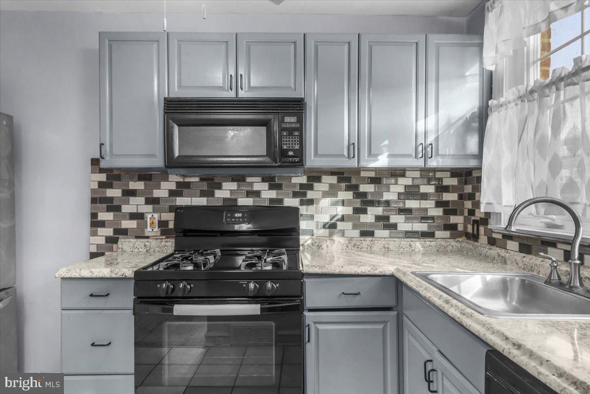 7823 Forrest Avenue Philadelphia, PA 19150 - Photo 9 of 27 a kitchen with stainless steel appliances granite countertop a stove a sink and a microwave